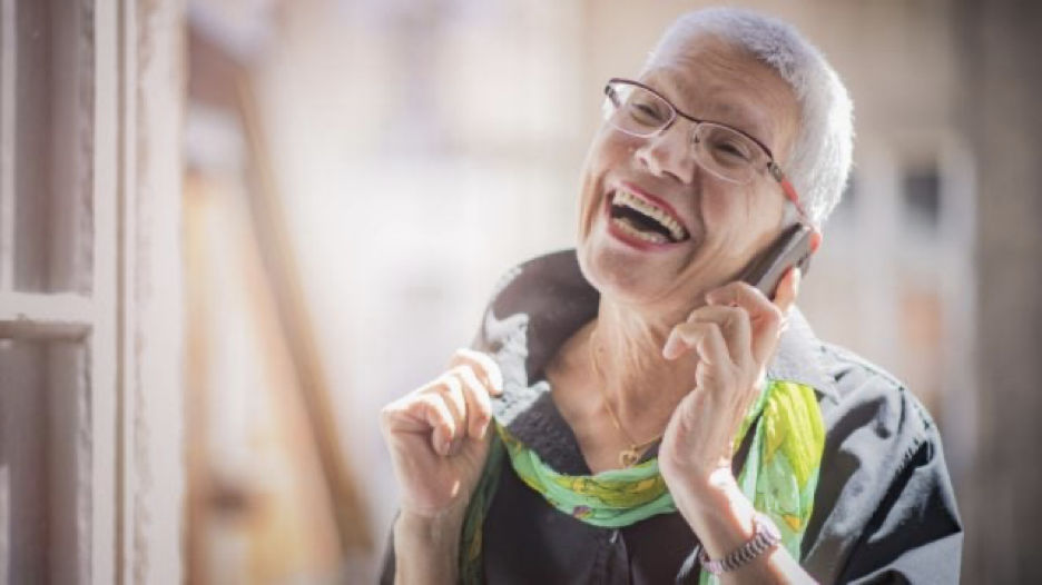 Elderly woman smiling as she enjoys a call on her cell phone