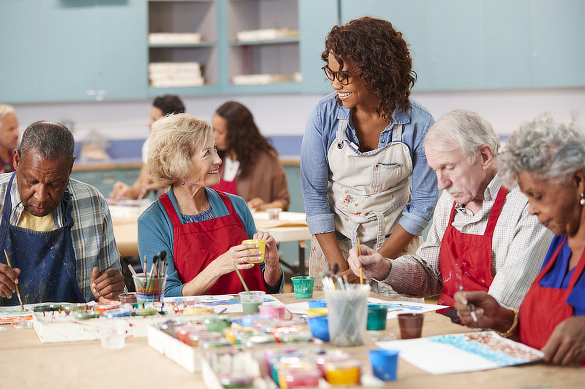 Group Of Retired Seniors Attending Art Class In Community Centre With Teacher. 